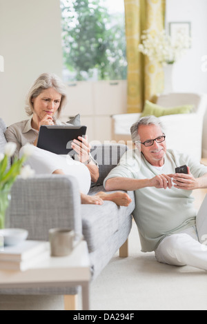Senior couple using digital tablet and cell phone at home Stock Photo