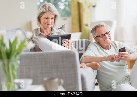 Senior couple using digital tablet and cell phone at home Stock Photo