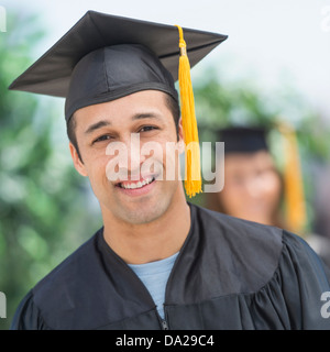 Portrait of male student on graduation ceremony with female student in background Stock Photo