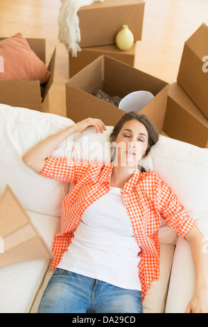 Young woman resting on sofa after moving into new home Stock Photo