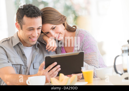 Young couple using digital tablet at kitchen table Stock Photo