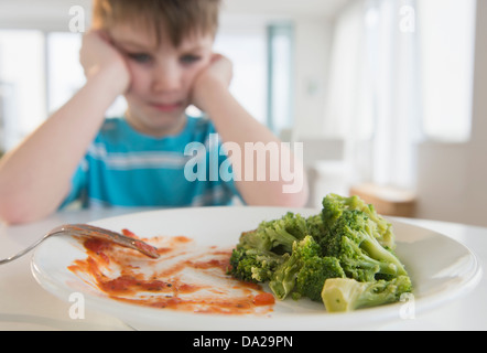 Portrait of boy (4-5) annoyed to eat broccoli Stock Photo