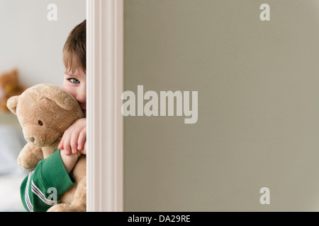 Portrait of boy (4-5) hiding behind wall Stock Photo