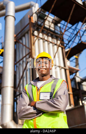 cheerful afro american oil industrial worker with arms crossed in refinery plant Stock Photo