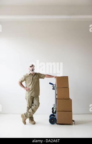 Portrait of delivery man standing next to push cart Stock Photo