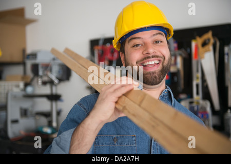 Portrait of smiling worker, holding boards on his shoulder Stock Photo