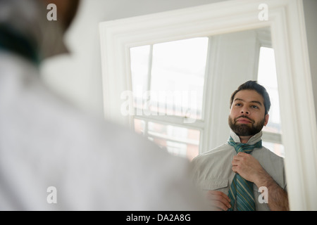 Reflection of man tying tie Stock Photo