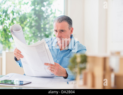 Portrait of man looking at blueprints in office Stock Photo