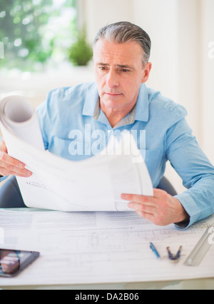 Portrait of man looking at blueprints in office Stock Photo