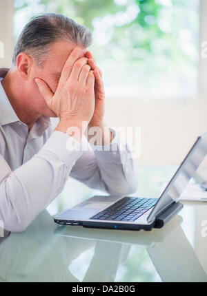 Portrait of tired man working on laptop Stock Photo