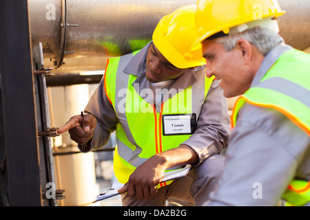 two mechanical engineers working on fuel pipeline in plant Stock Photo