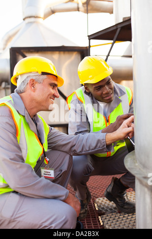 two petrochemical technicians inspecting fuel tank in plant Stock Photo
