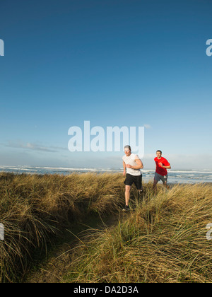 USA, Oregon, Rockaway Beach, Young adult men running on dune Stock Photo