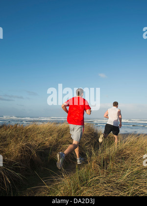 USA, Oregon, Rockaway Beach, Young adult men running on dune Stock Photo