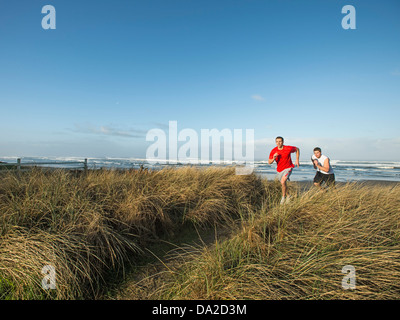 USA, Oregon, Rockaway Beach, Young adult men running on dune Stock Photo