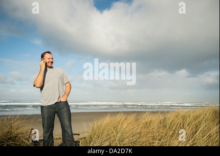 USA, Oregon, Rockaway Beach, Man on phone while standing on beach Stock Photo