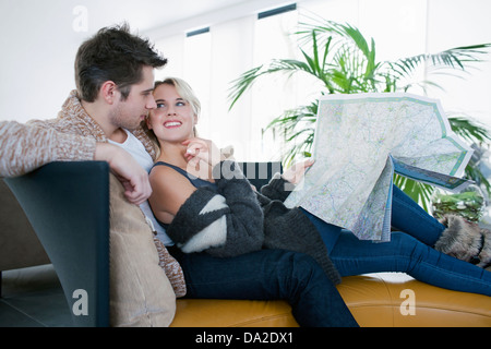 Couple sitting on sofa and reading map Stock Photo