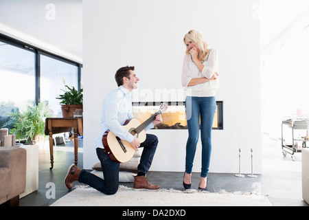 Man playing guitar in front of woman Stock Photo