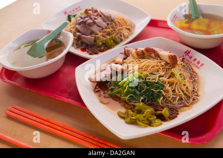 Two plates of Chinese food, one with roast duck and noodles, the other with crispy belly pork, Bugis, Singapore Stock Photo