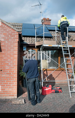 engineers fitting solar pv cells to bungalow roof Stock Photo