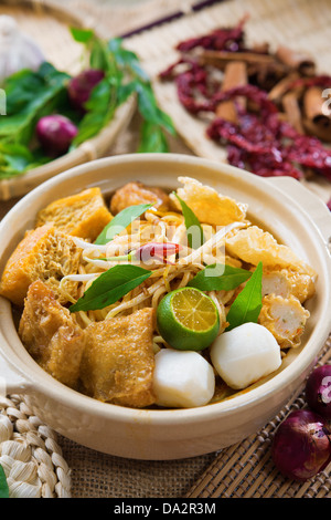 Hot and spicy Singaporean Curry Noodle or laksa mee in clay pot, decoration setup, serve with chopsticks. Singapore cuisine. Stock Photo