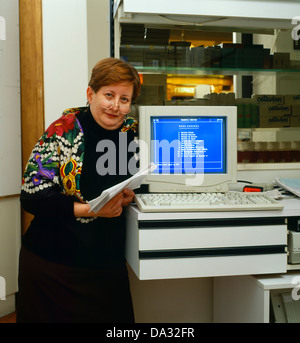 Chubby woman standing by computer, pharmacy office Stock Photo