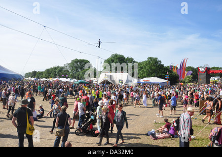 A tightrope walker walks overhead a crowd in the circus area of Glastonbury Festival of Contemporary Performing Arts 2013. Stock Photo