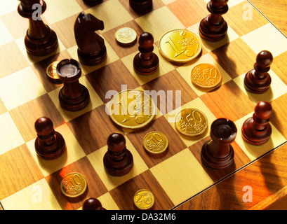 Chessmen and golden Euro coins on chessboard Stock Photo