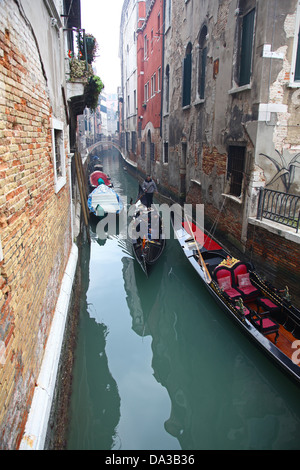 Gondolas and gondoliers on a small side Canal with colourful old buildings Venice Italy in winter Stock Photo