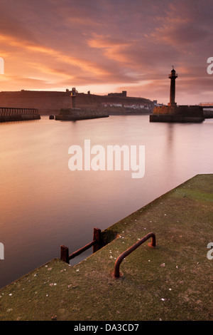 View of the river Esk and Whitby Harbour from the west pier at dawn in winter, with the distant Abbey and St Mary's church on th Stock Photo
