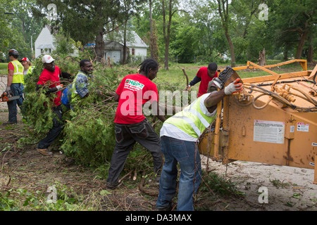 Workers feed bush and small trees into a chipper as the Detroit Blight Authority cleans up the Brightmoor neighborhood. Stock Photo