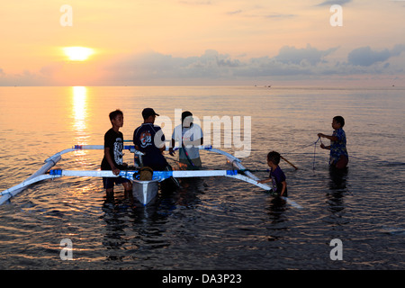 A family of fishermen with their boat and nets at sunset. Anturan Village, Lovina, north Bali, Indonesia Stock Photo