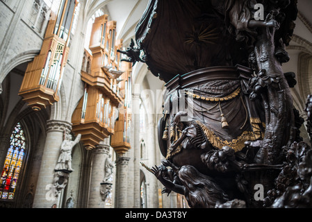 BRUSSELS, Belgium — The ornately carved wooden pulpit at the Cathedral of St. Michael and St. Gudula (in French, Co-Cathédrale collégiale des Ss-Michel et Gudule) with the pipe organ in the background. A church was founded on this site in the 11th century but the current building dates to the 13th to 15th centuries. The Roman Catholic cathedral is the venue for many state functions such as coronations, royal weddings, and state funerals. It has two patron saints, St Michael and St Gudula, both of whom are also the patron saints of Brussels. Stock Photo