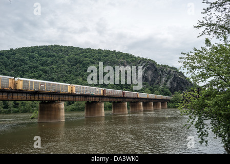 HARPERS FERRY, West Virginia, United States — A freight train crosses the historic railroad bridge over the Potomac River at Harpers Ferry. This active railway, set against the backdrop of the Blue Ridge Mountains, demonstrates the continued importance of Harpers Ferry as a transportation hub, blending 19th-century infrastructure with modern commerce. Stock Photo