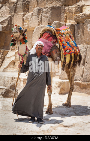 Man and camel beside Great Pyramid of Giza, also known as Pyramid of Khufu and Pyramid of Cheops, Giza, Cairo, Egypt Stock Photo