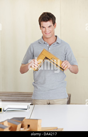Happy carpenter holding a window frame sample in his work shop Stock Photo