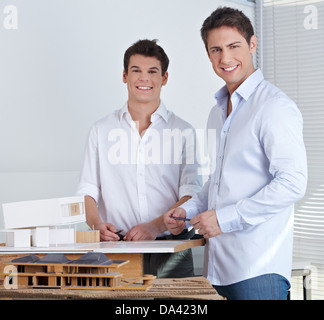 Two happy architects in their office with model of a modern house Stock Photo