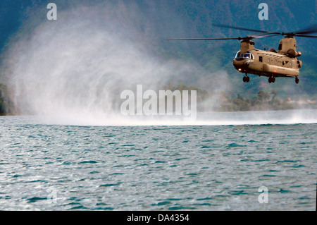 A US Army CH-47F Chinook helicopter with the 25th Combat Aviation Brigade drops Navy SEAL Special Warfare Group 3 commandos into the water during HELOCAST training at Marine Corps Air Station Kaneohe Bay June 19, 2013 in Hawaii. Stock Photo