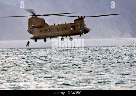 A US Army CH-47F Chinook helicopter with the 25th Combat Aviation Brigade drops Navy SEAL Special Warfare Group 3 commandos into the water during HELOCAST training at Marine Corps Air Station Kaneohe Bay June 19, 2013 in Hawaii. Stock Photo