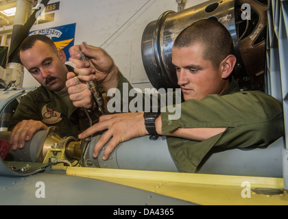 Sgt. Brian Richardson and Cpl. Christopher Hernandez, assigned to the Dragons of Marine Medium Tiltrotor Squadron (VMM) 265, perform maintenance on a UH-1Y Huey helicopter in the hangar bay aboard the forward-deployed amphibious assault ship USS Bonhomme Stock Photo