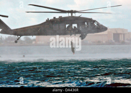 A US Army UH-60 Black Hawk helicopter with the 25th Combat Aviation Brigade drops Navy SEAL Special Warfare Group 3 members into the water during HELOCAST training at Marine Corps Air Station Kaneohe Bay June 19, 2013 in Hawaii. Stock Photo