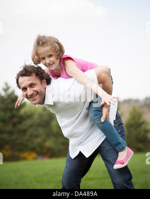 Father giving young daughter piggyback ride Stock Photo