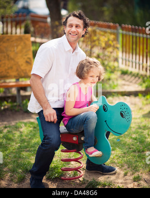 Father and daughter on playground spring rider Stock Photo