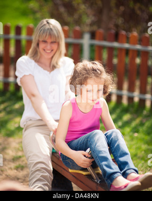 Mother and daughter ride seesaw together Stock Photo