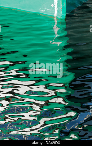 Green hull of a boat with artistic reflection in the water Stock Photo