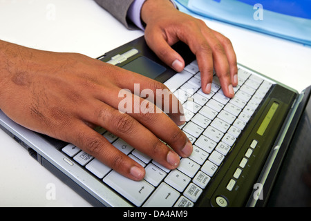 Close up of Indian mans hands typing on laptop Stock Photo
