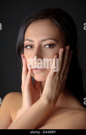 Portrait of young attractive brunnete woman holding her face in her hands with sugar on her lips Stock Photo