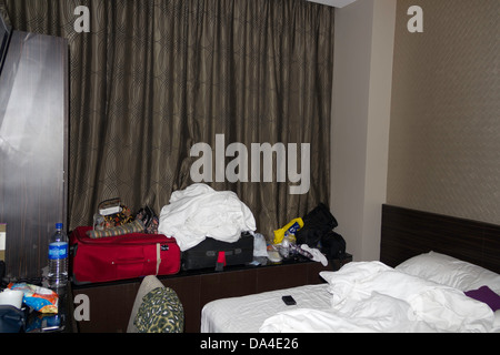 An occupied hotel room inside the V Hotel in Singapore, with the bed disturbed and luggage open, a small room in the hotel Stock Photo
