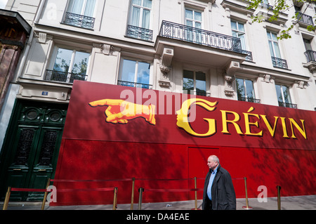 Man walking past sign for Grevin Wax museum, Paris Stock Photo
