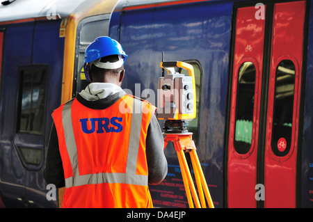 A worker standing next to survey equipment at Bristol Temple Meads railway station at the side of a First Great Western train Stock Photo